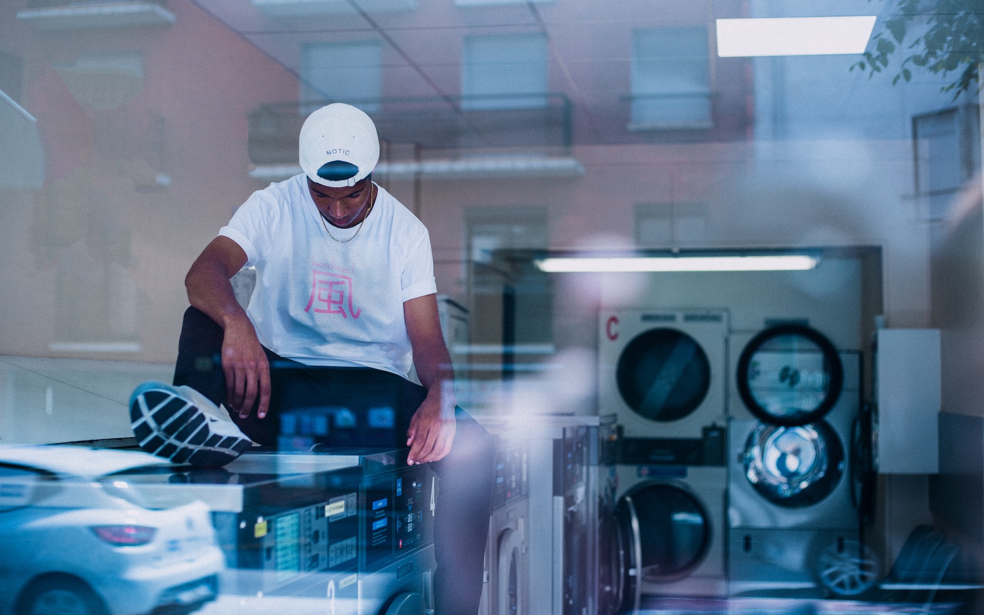teen sitting on top of washing machine at laundromat