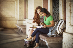 Two teens studying on a bench