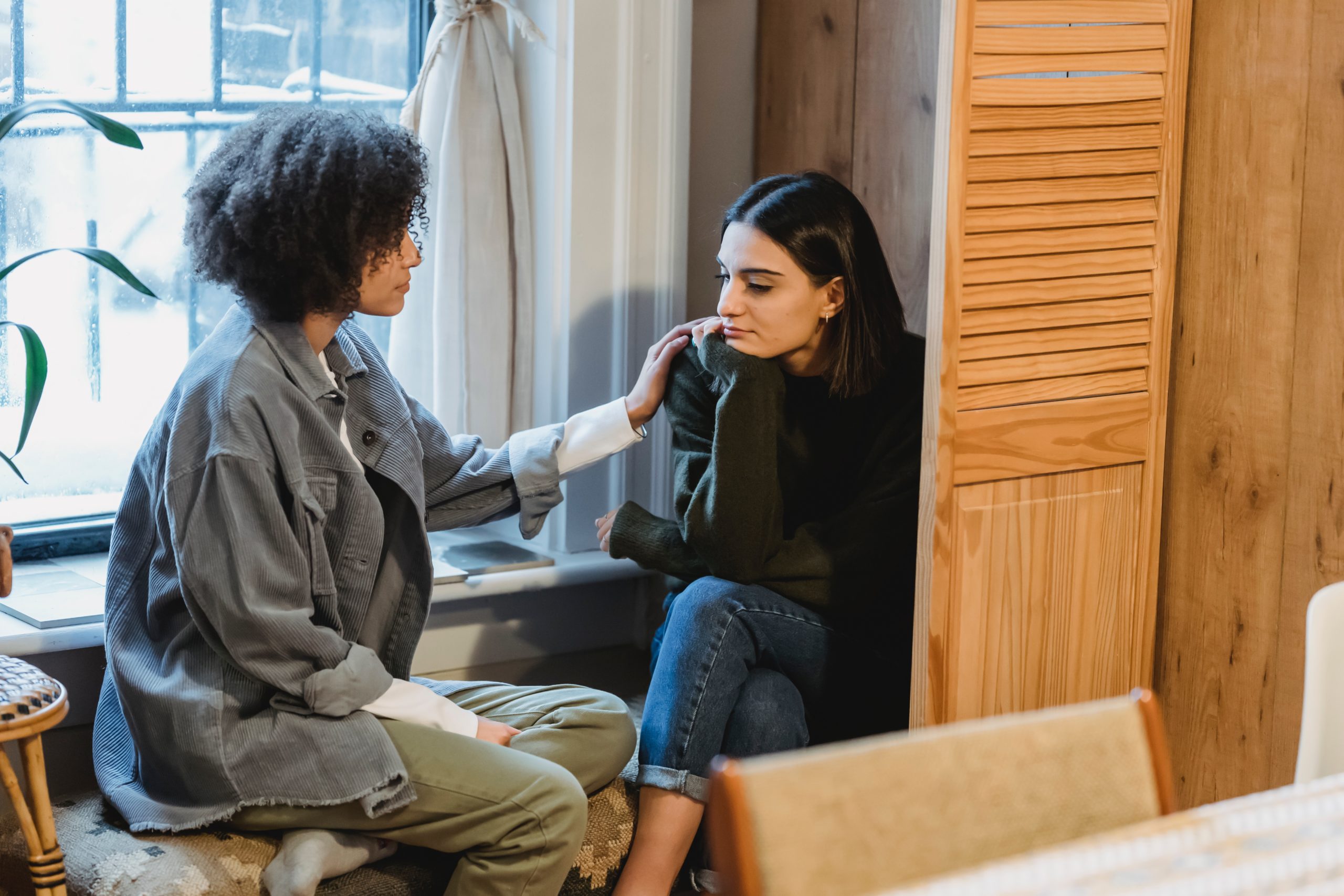 A young adult consoling her friend in an apartment