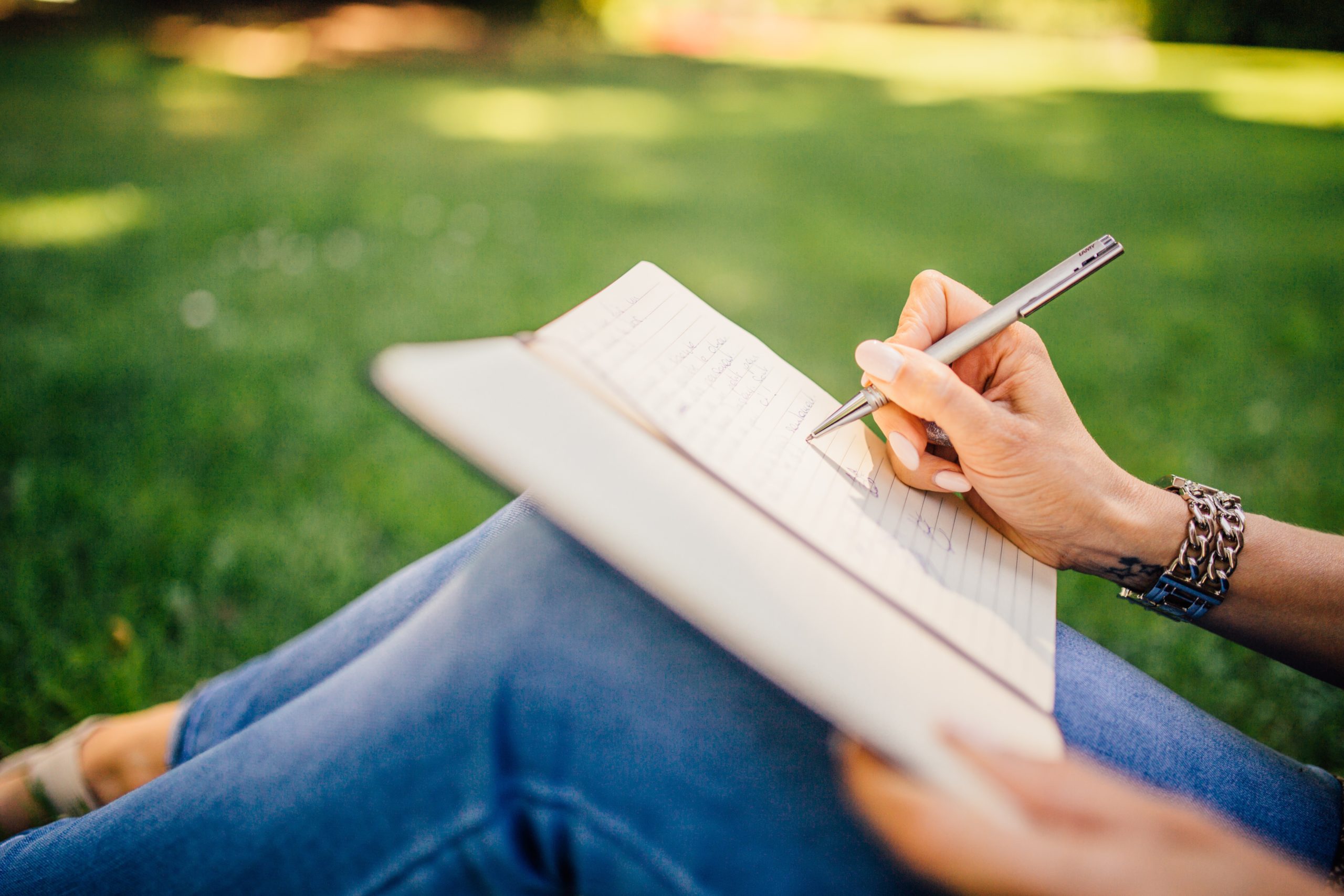 Woman sitting on the grass writing in her journal