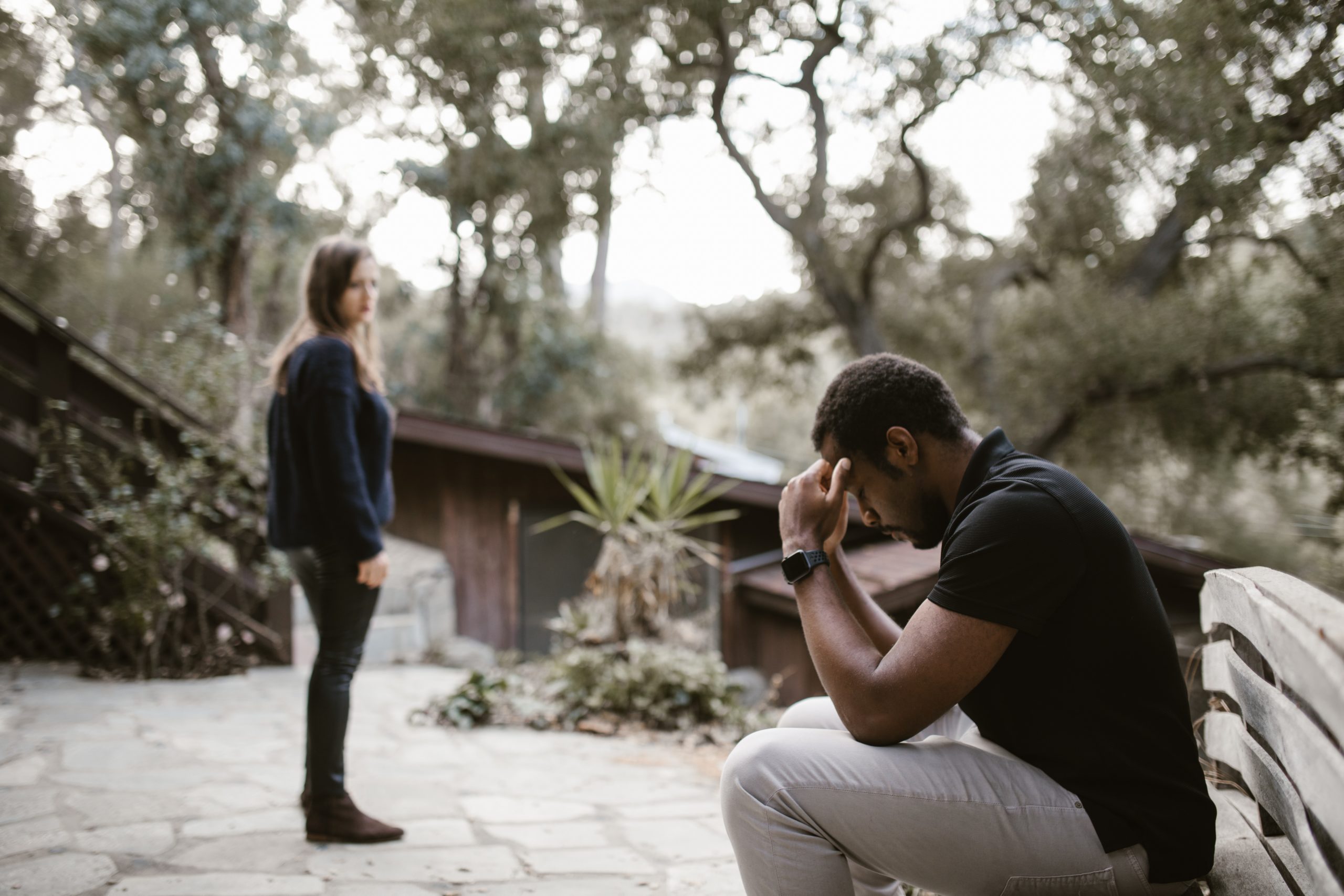 A woman walking away from a man in the park after breaking up