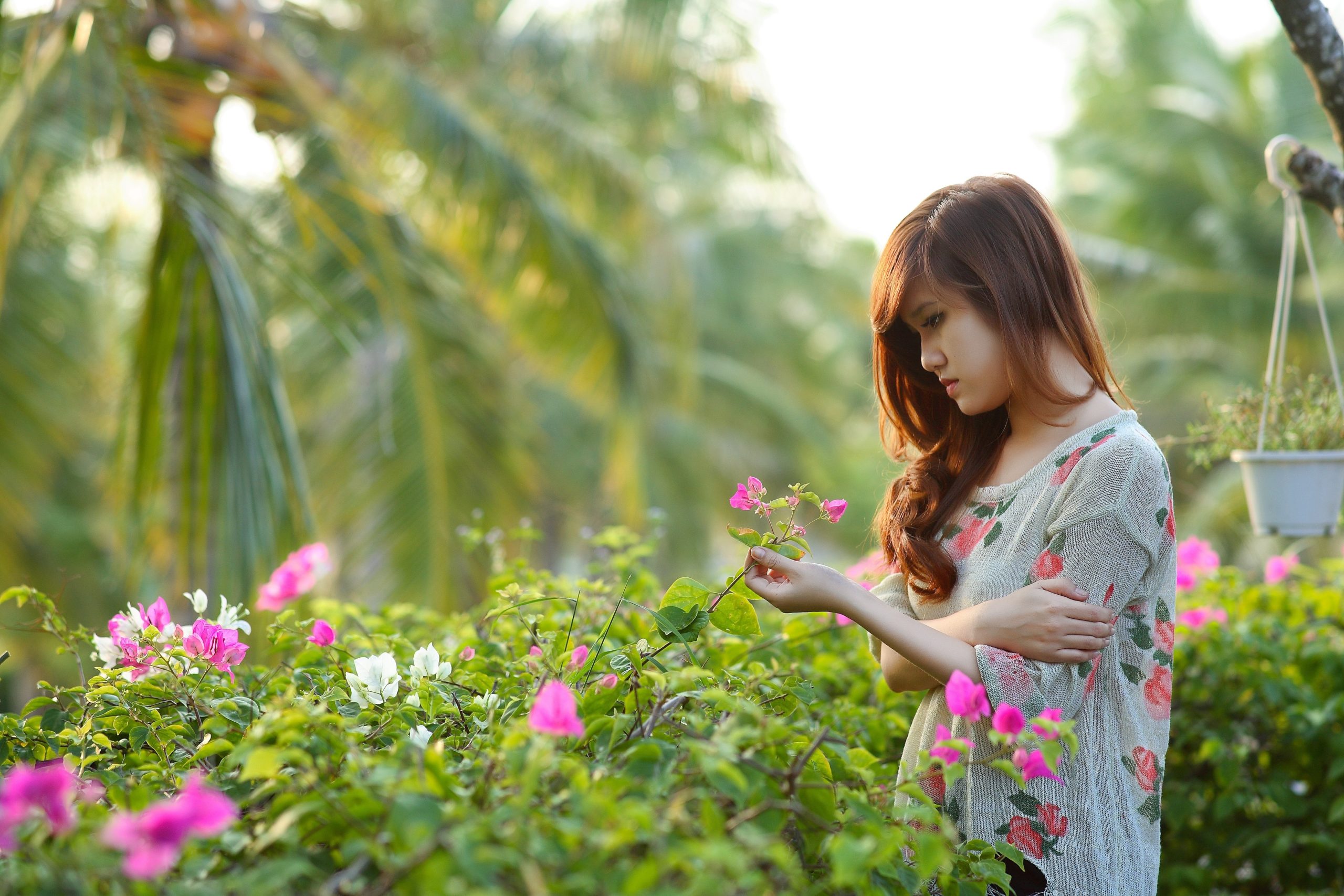Woman looking sad looking at flowers in a garden