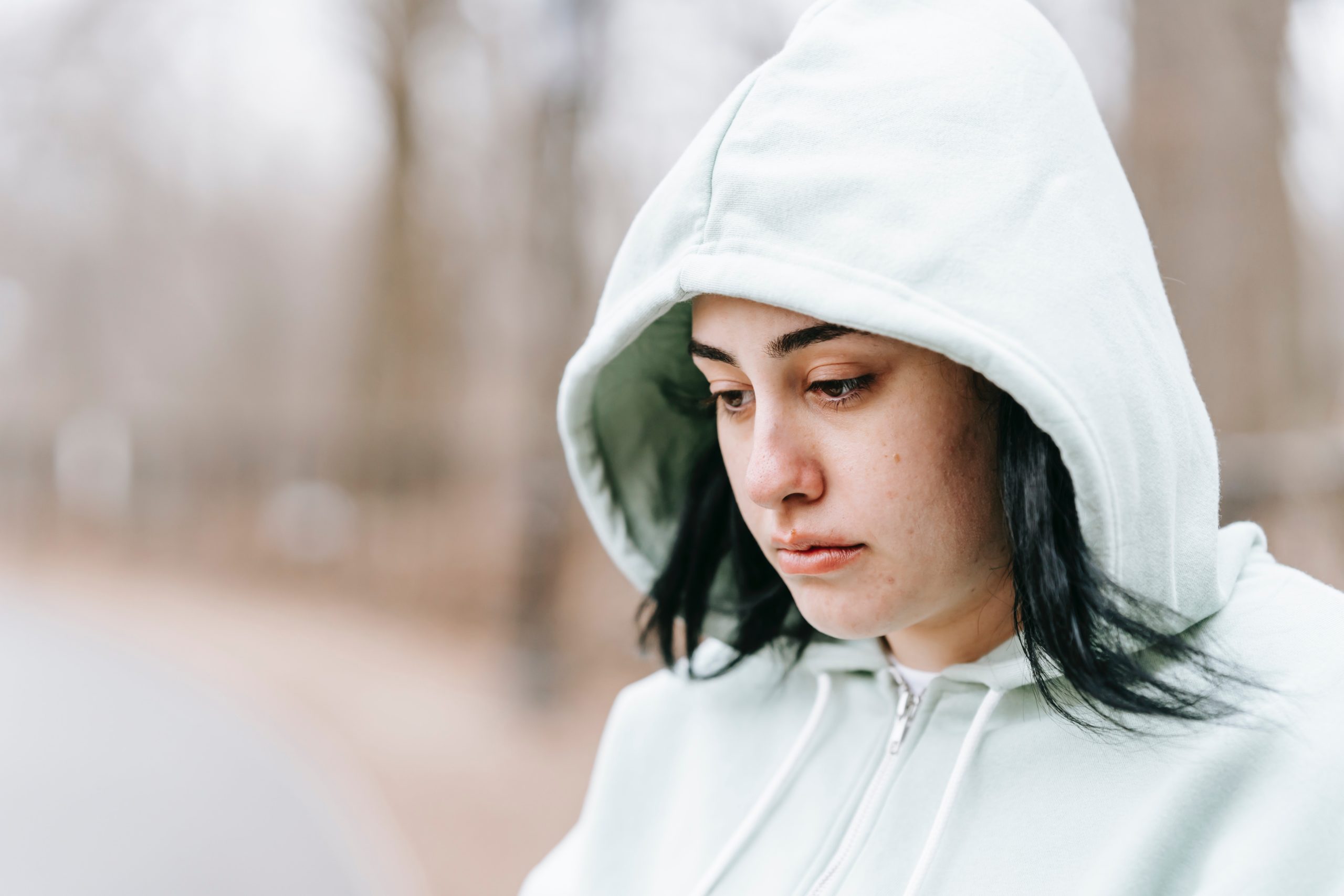 Woman wearing a hoodie feeling hopeless, looking at the ground