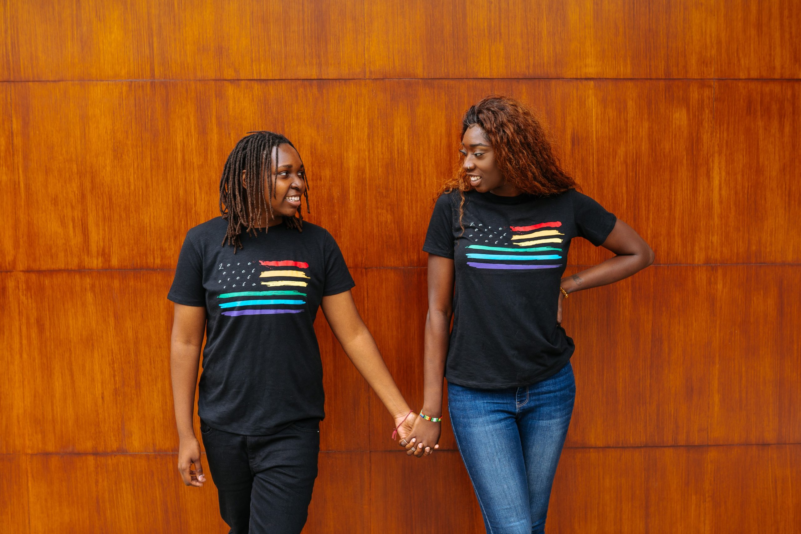 A couple holding hands, wearing pride t shirts