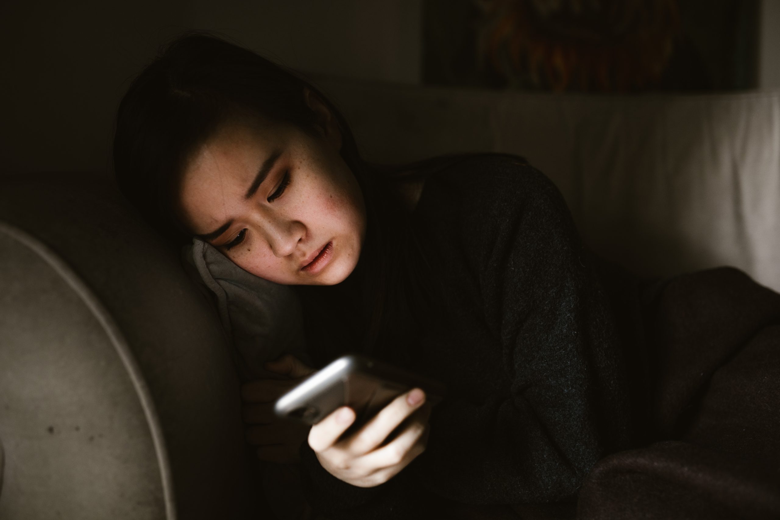 Girl lying on a couch looking in distress on her phone