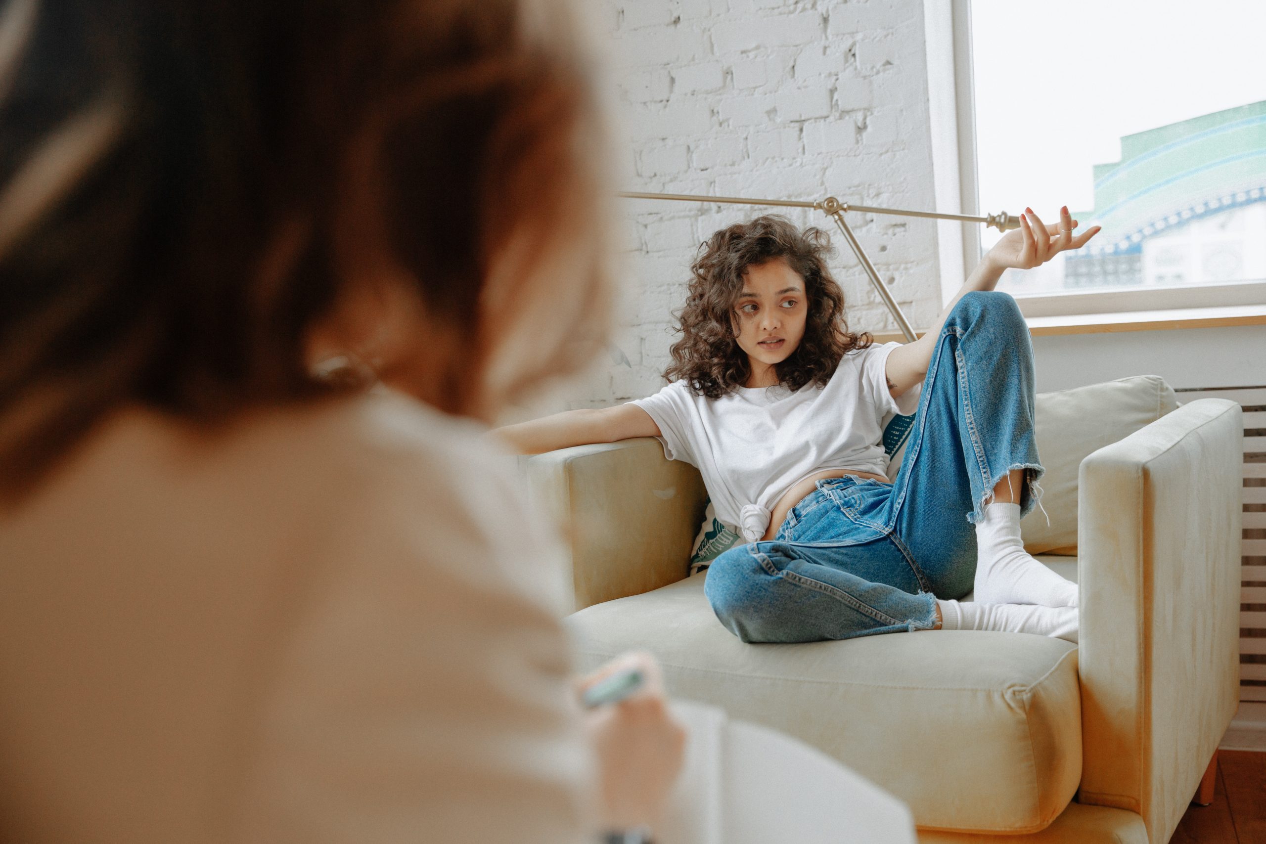 Girl sitting on a couch talking to her therapist at a therapy session