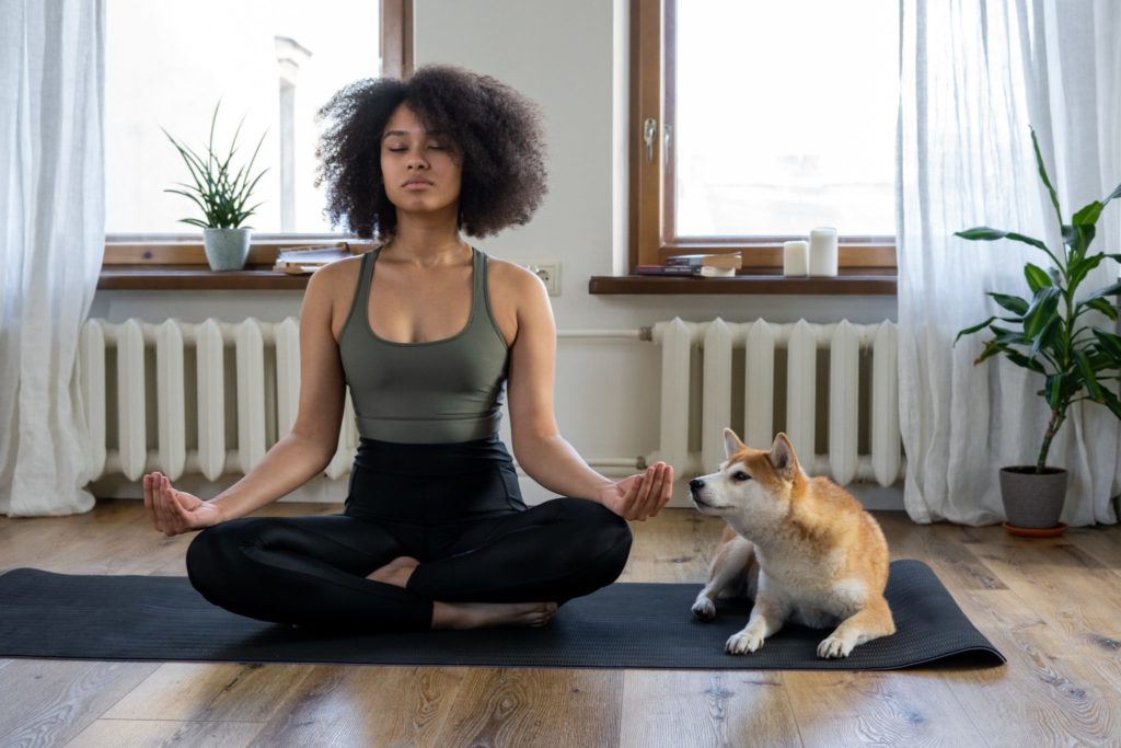 Woman practicing yoga next to her dog
