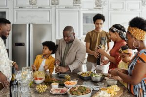 black family preparing a meal together at the kitchen counter with men, women and children all actively involved