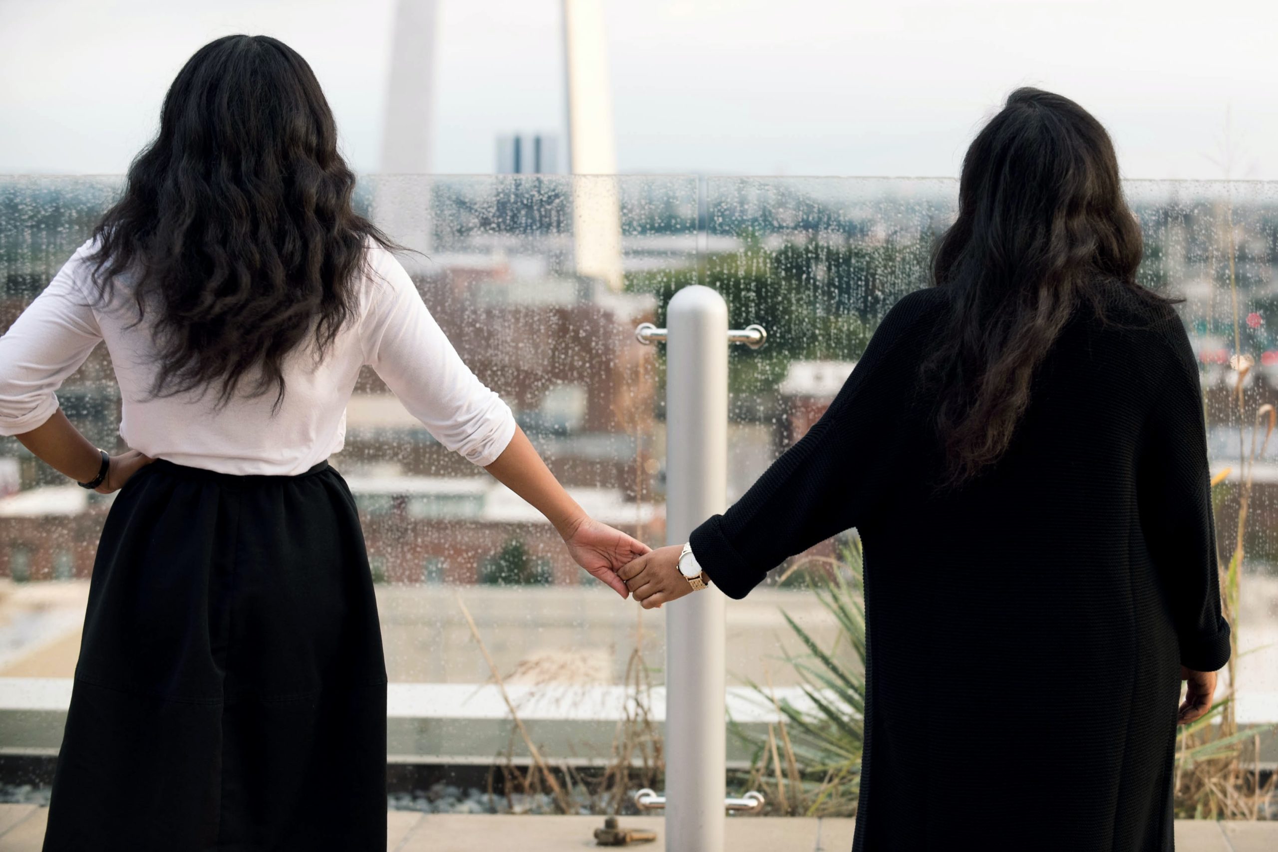 two women holding hands while looking out over