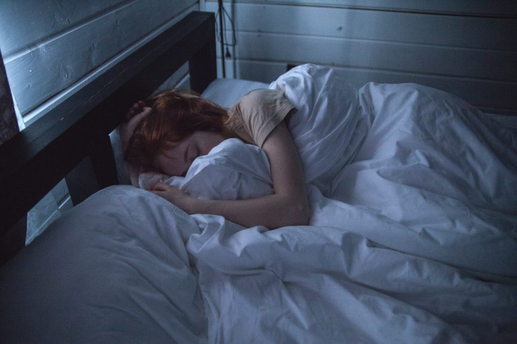 young adult woman sleep in bed in dark room