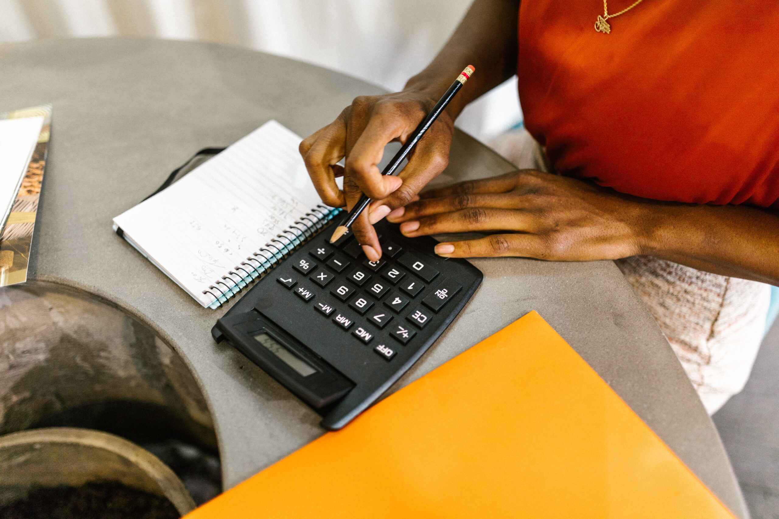 woman calculating her budget with a calculator, notepad and pencil
