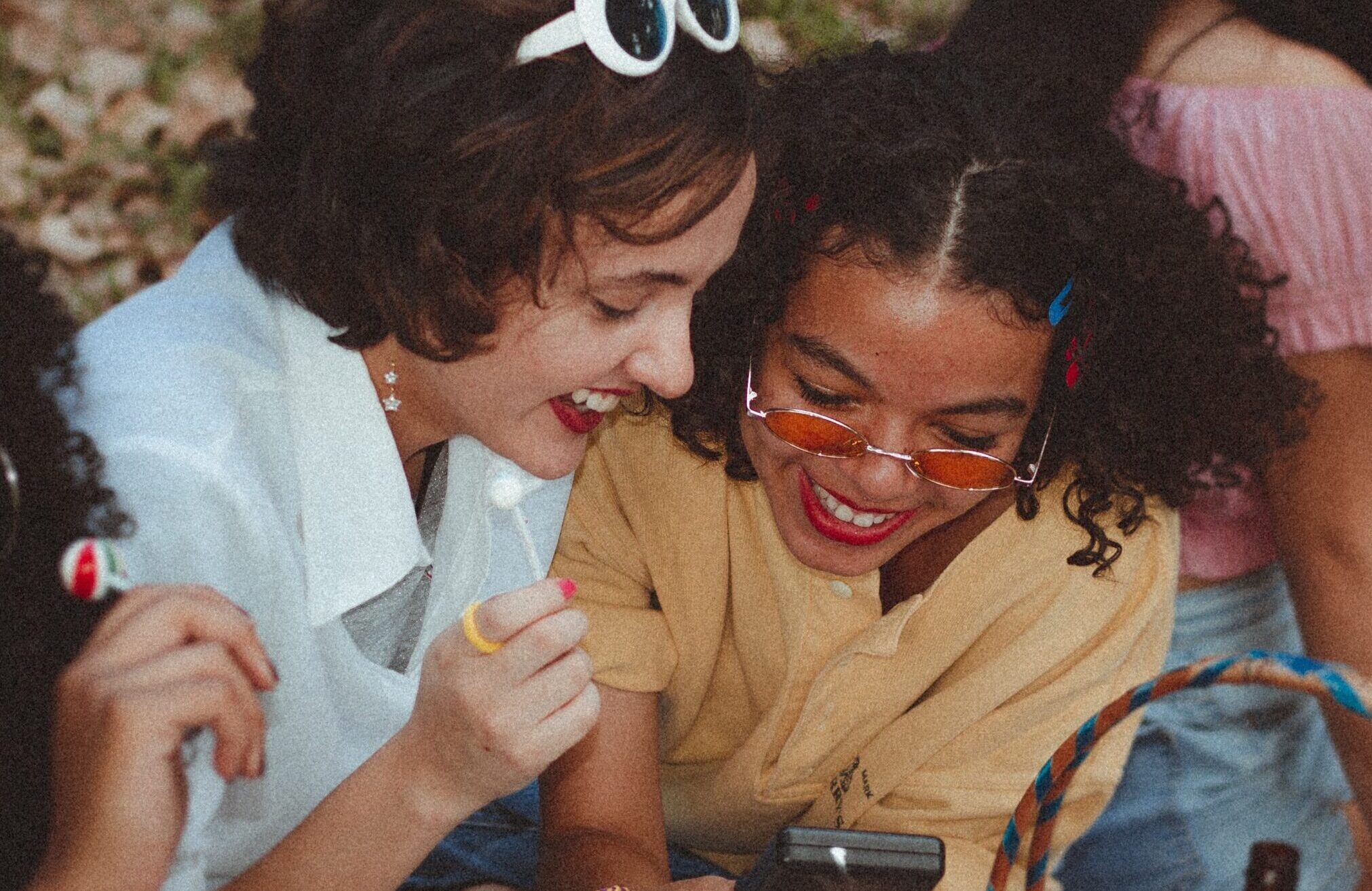 Two young women smiling while looking at a phone together