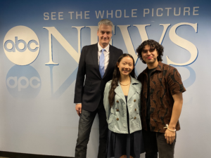 adult and two students standing together in front of abc news backdrop