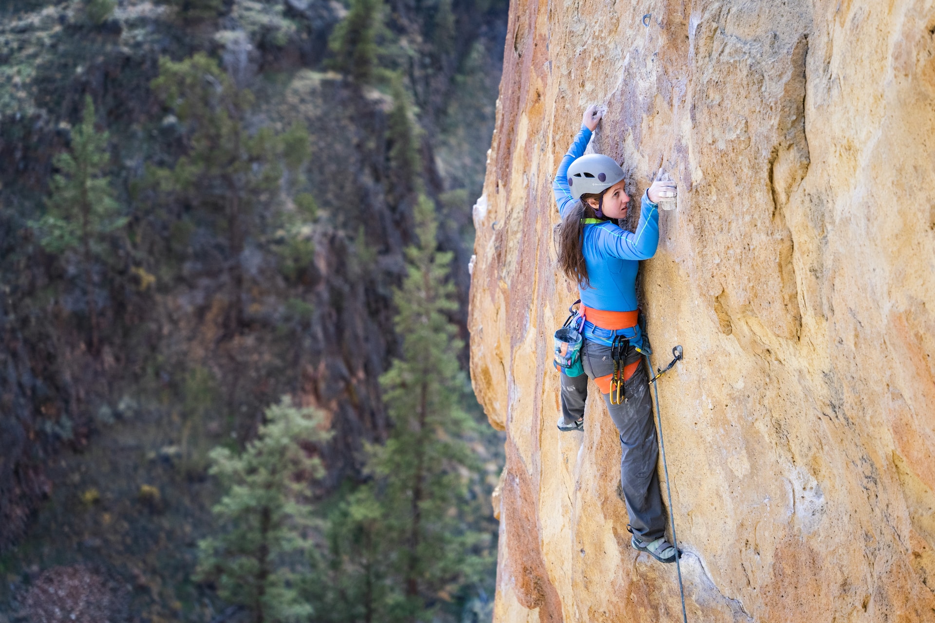 young woman scaling a outdoor rock wall