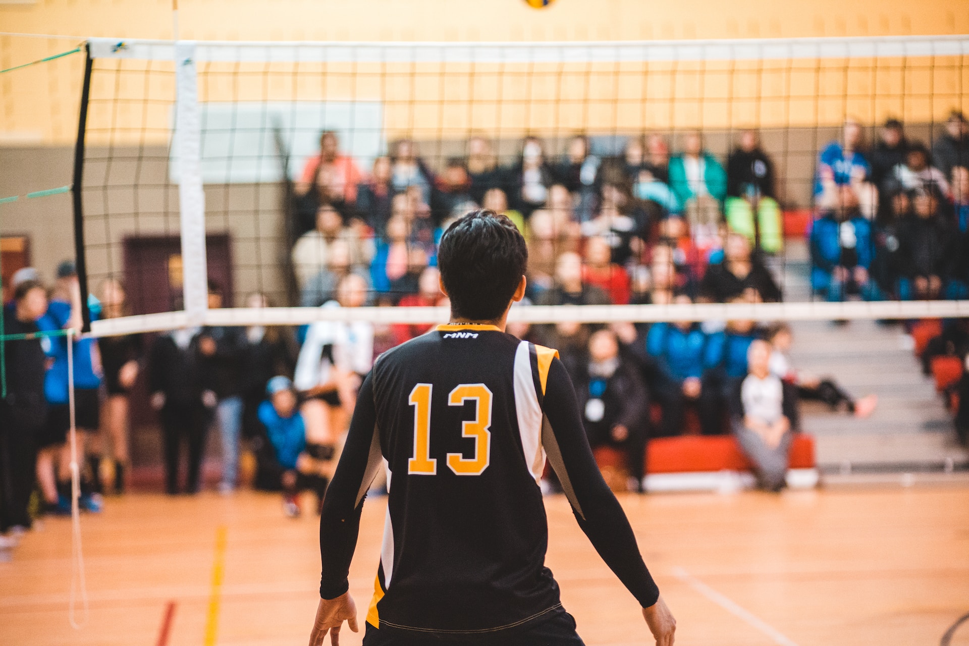 student playing college sport, standing in front of volleyball net