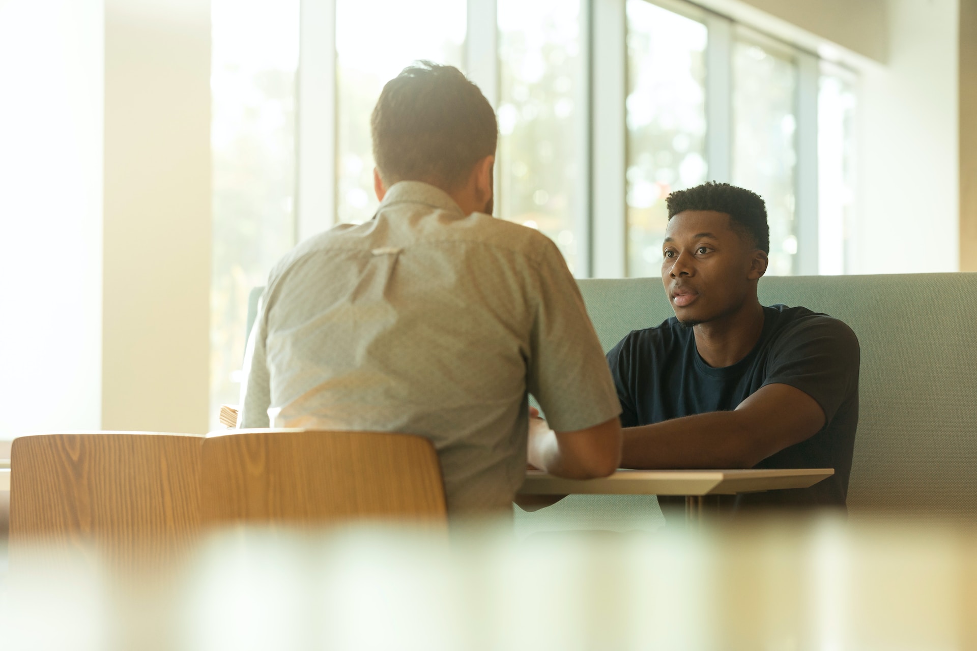college student speaking with his mentor while seated at a table
