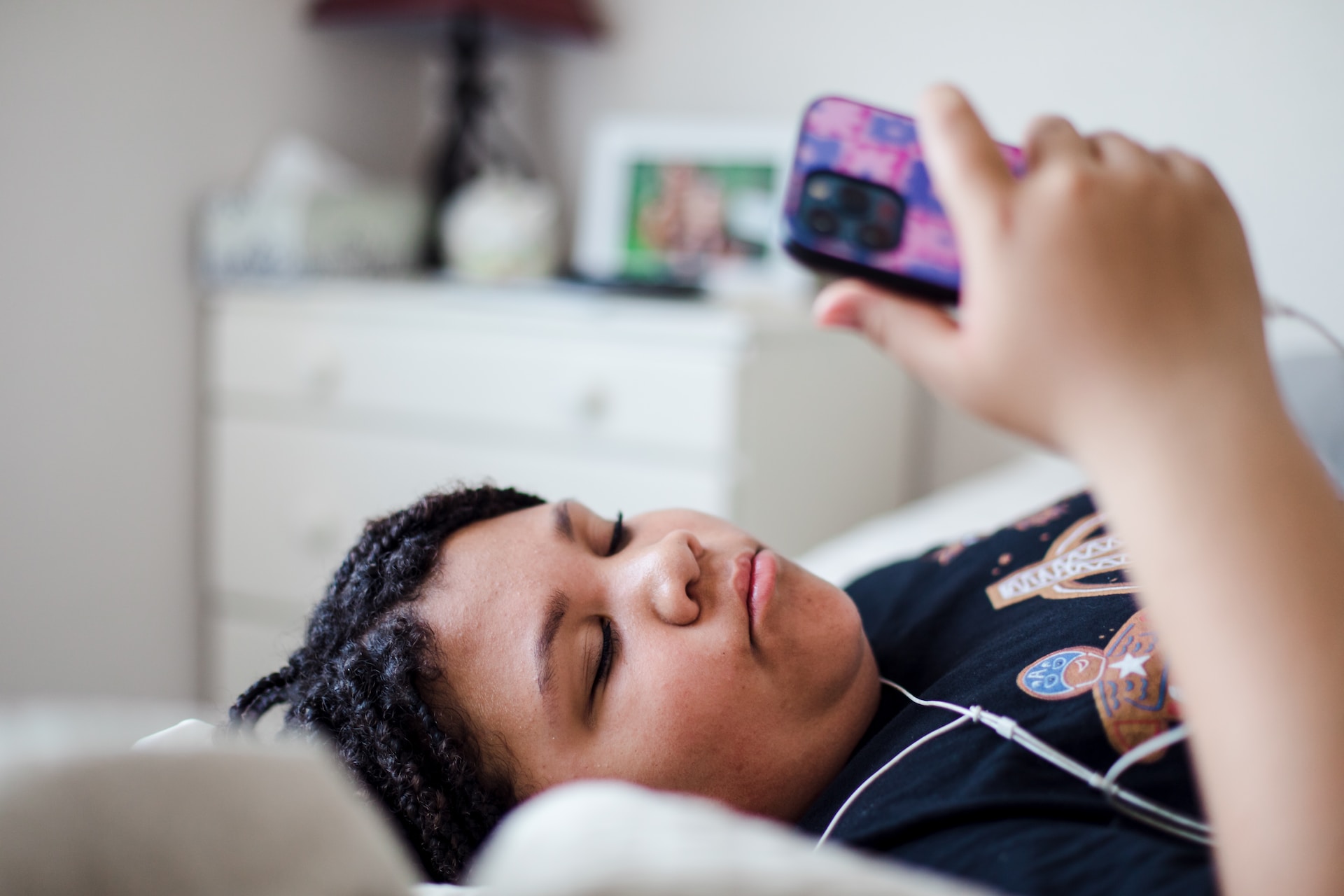 A teen girl laying on a bed with a cell phone