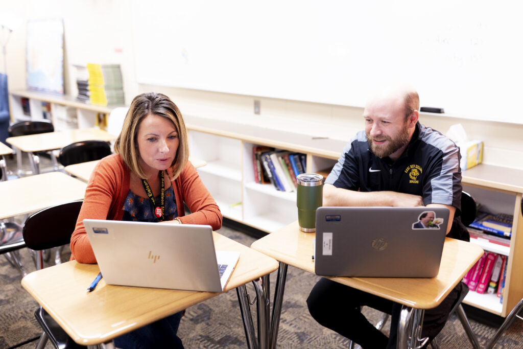 Staff members of Fargo Public Schools sit in front of their laptops and engage in lively conversation.