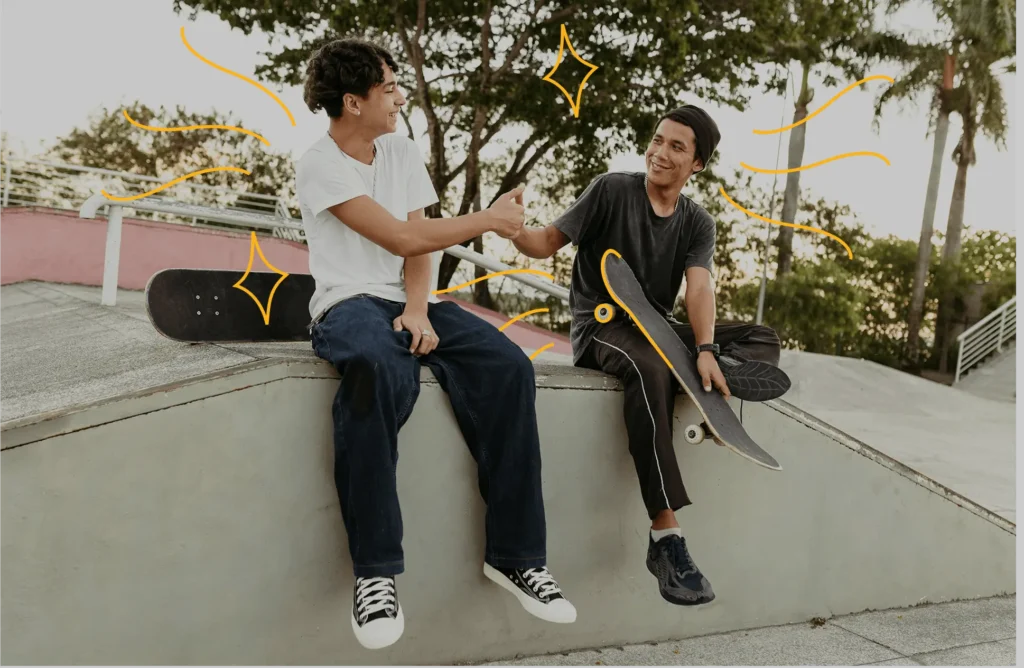 Young men shaking hands sitting on a wall with skateboards