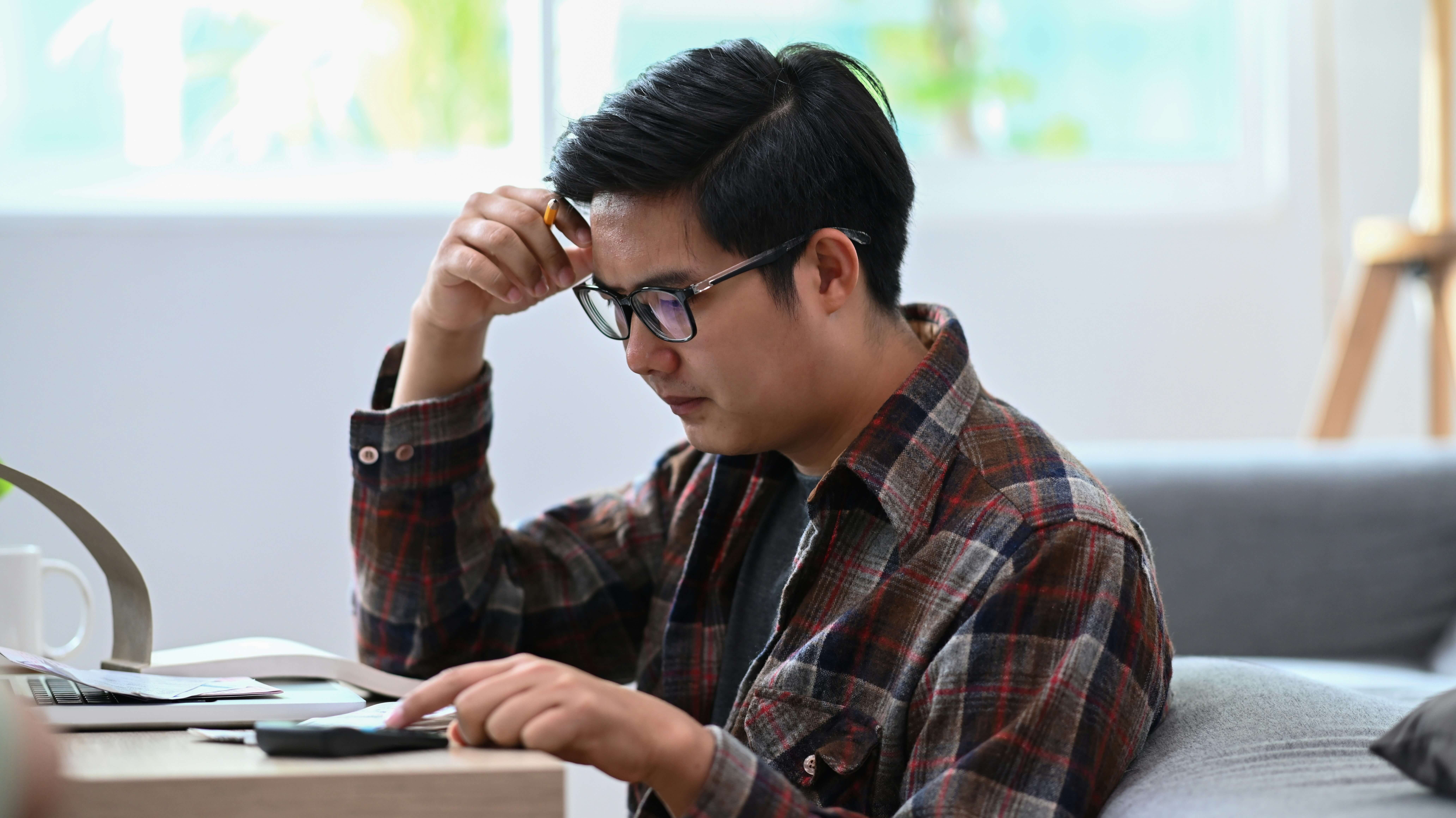 A stressed young man is sitting at a desk